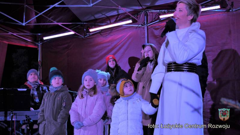Magda Steczkowska śpiewa na scenie z dziećmi.
