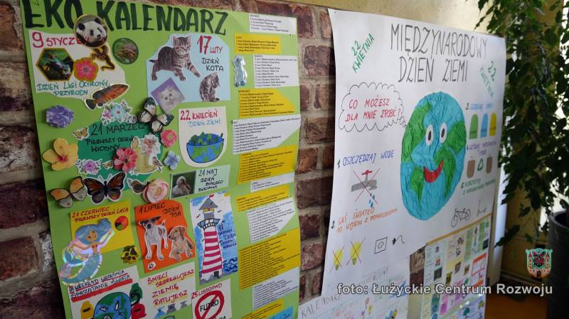 Plakaty o eko kalendarzu i międzynarodowym dniu ziemi wiszą na ceglanej ścianie.