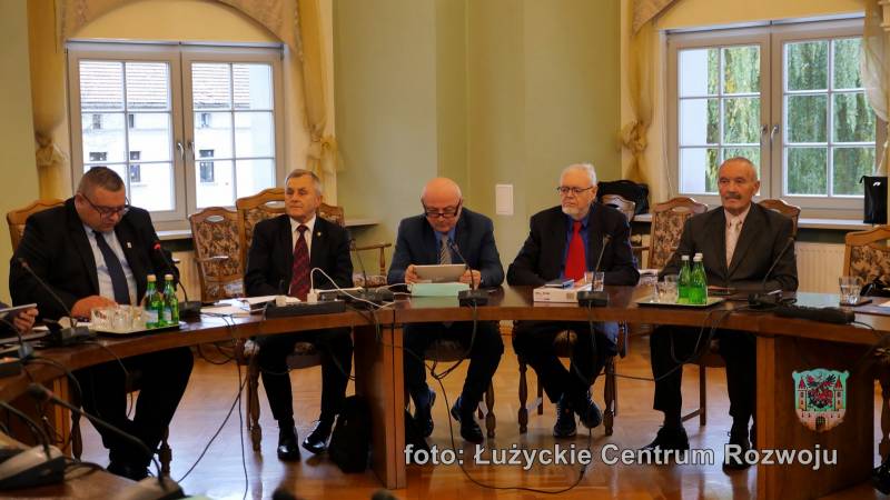 Pięciu mężczyzn - radnych Rady Miasta Lubań, w ciemnych garniturach, siedzą przy stole