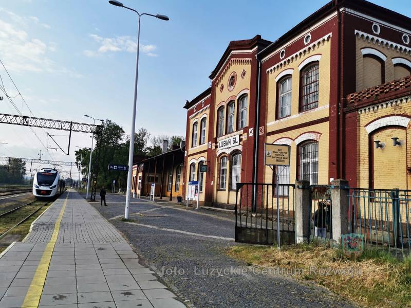 brązowo-beżowy budynek dworca kolejowego, po lewej pociąg