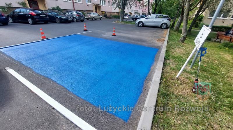 niebieski prostokąt namalowany na asfalcie - miejsce parkingowe dla niepełnosprawnych w trakcie malowania