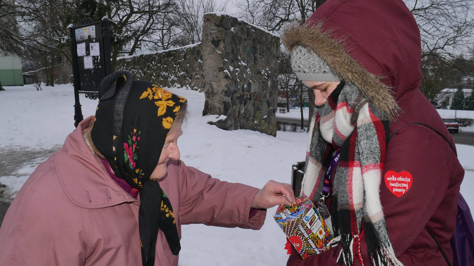 Kobieta wrzuca do skarbonki WOŚP monetę